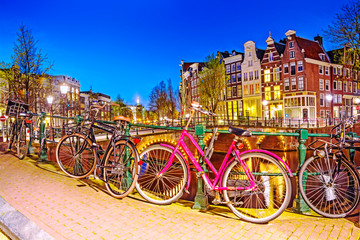 Fototapeta premium Bicycle parked on a bridge in Amsterdam at night, Netherlands
