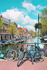 Fototapeta premium Amsterdam street scene. Old bicycle standing on a bridge next to a canal. Amsterdam, Netherlands
