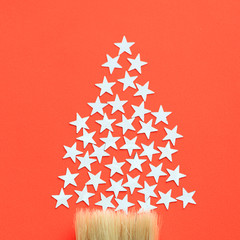 Stars shine in the form Christmas tree silhouette on red background. Minimal composition with copy...