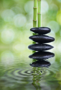 Zen stones with green bamboo on wooden table with green blur bokeh background
