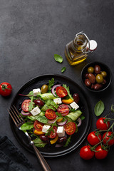 Fototapeta na wymiar salad with tomato, cucumber, bel pepper , olives and feta cheese on black plate