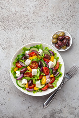 greek salad with tomato, cucumber, bel pepper, olives  and feta cheese in white bowl