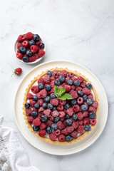 blueberry  and raspberry tart  on white marble background