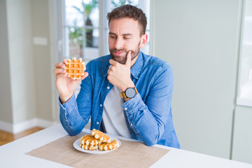 Handsome man eating sweet Belgian pancakes serious face thinking about question, very confused idea