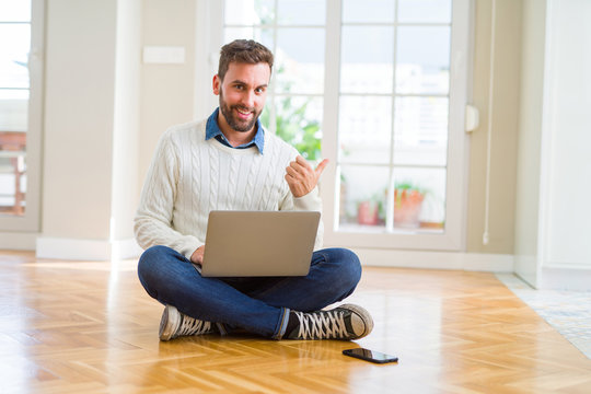 Handsome man wearing working using computer laptop pointing and showing with thumb up to the side with happy face smiling