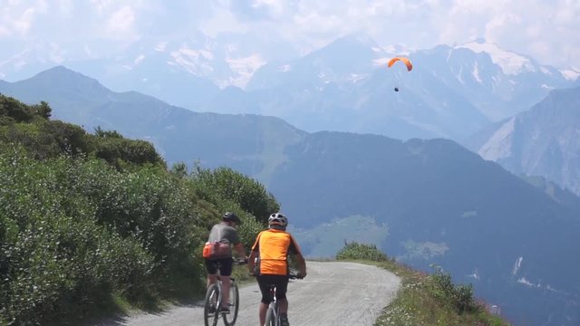 Two extreme paragliders flying in the distance against a clear blue sky in Switzerland. Adventurers in the sky over the Alps. People fly in the sky. Two paratroopers soar above the villages. Hobbies 