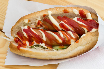 Fast food concept: hot dog with two sausages and ketchup on the table. Top view