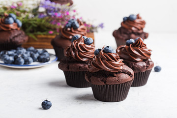 Chocolate cupcakes with blueberries on white table, close up