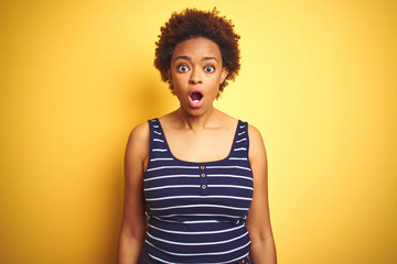 Beauitul african american woman wearing summer t-shirt over isolated yellow background afraid and shocked with surprise and amazed expression, fear and excited face.