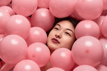 Fototapeta na wymiar Ethnic lady under pink balloons