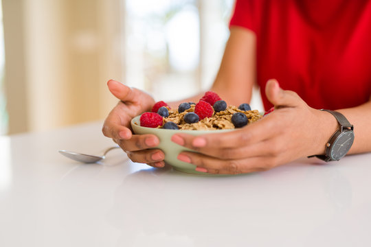 Close up of young woman eating healthy cereals and berries for breakfast