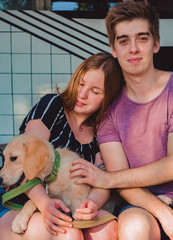 The young married loving couple walks with the little dog in the park. Golden retriever. 