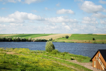 Fototapeta na wymiar Pond on a summer morning, agricultural fields and trees on the opposite shore
