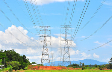 High voltage lines and power pylons tower on a sunny day with clouds in the blue sky