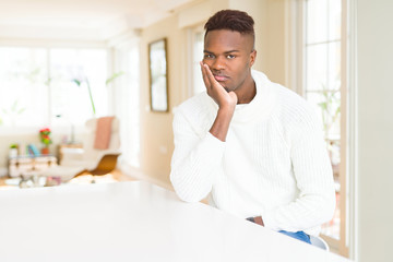 Handsome african american man on white table thinking looking tired and bored with depression problems with crossed arms.