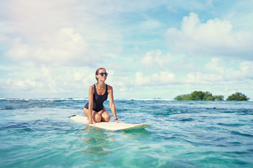 Hobby and vacation. Young sexy woman swimming over surfboard in clear blue water at  beach, Siargao Island, Philippines.