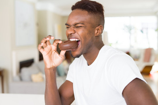 African american man eating  and enjoying a sweet chocolate donut