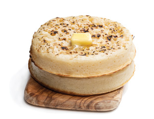 Giant crumpets with melted butter on cutting board isolated on white