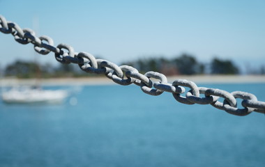 Iron chain on ocean shore on sunny day