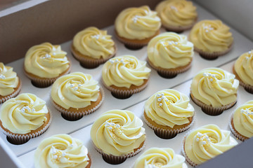 Delicious cupcakes in cardboard box with a hat in the form of a rose