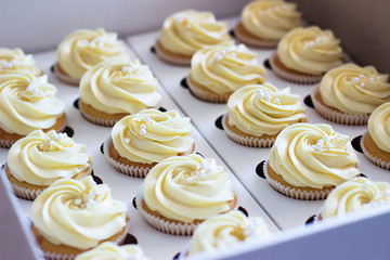 Delicious cupcakes in cardboard box with a hat in the form of a rose
