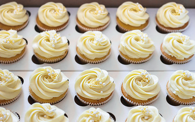 Delicious cupcakes in cardboard box with a hat in the form of a rose