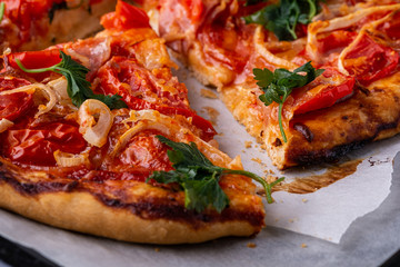 Freshly cooked hot pizza with cheese ham meat tomato onion parsley homemade on parchment paper recipe close up macro