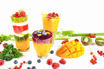 Wielowarstwowe smoothie w szklankach, wokół rozsypane owoce