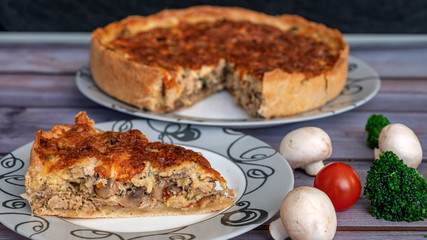 Chicken and mushroom pie, cut piece close-up, near tomatoes, mushrooms, broccoli