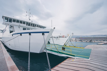 Naklejka premium Ferryboat loading or unloading by a port pier. Concept of transportation and traveling.