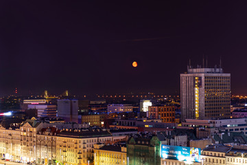 Fototapeta na wymiar Warsaw in the light of night lights and red moon