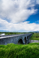 Montenegro, Beautiful emperors bridge building over zeta river water in niksic village enclosed by ountains and beautiful rural nature landscape with dramatic sky of thunderstorm