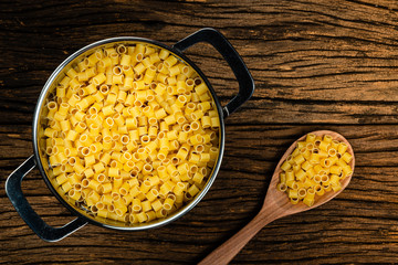 Pasta Our Father dough with eggs ready for cooking within drainer water. Old wooden background.