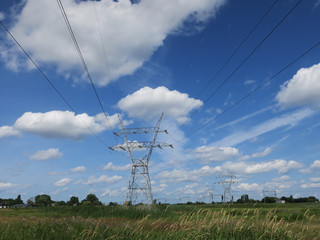 high-tension pine tower in the meadow against a blue sky