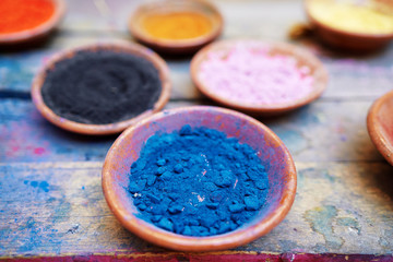 Travel by Morocco. Plates with natural colorful paint powder on wooden table.