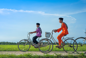 Obraz premium happy young local boy riding old bicycle at paddy field