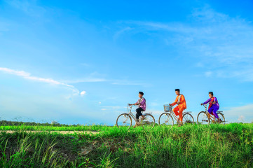 happy young local boy riding old bicycle at paddy field