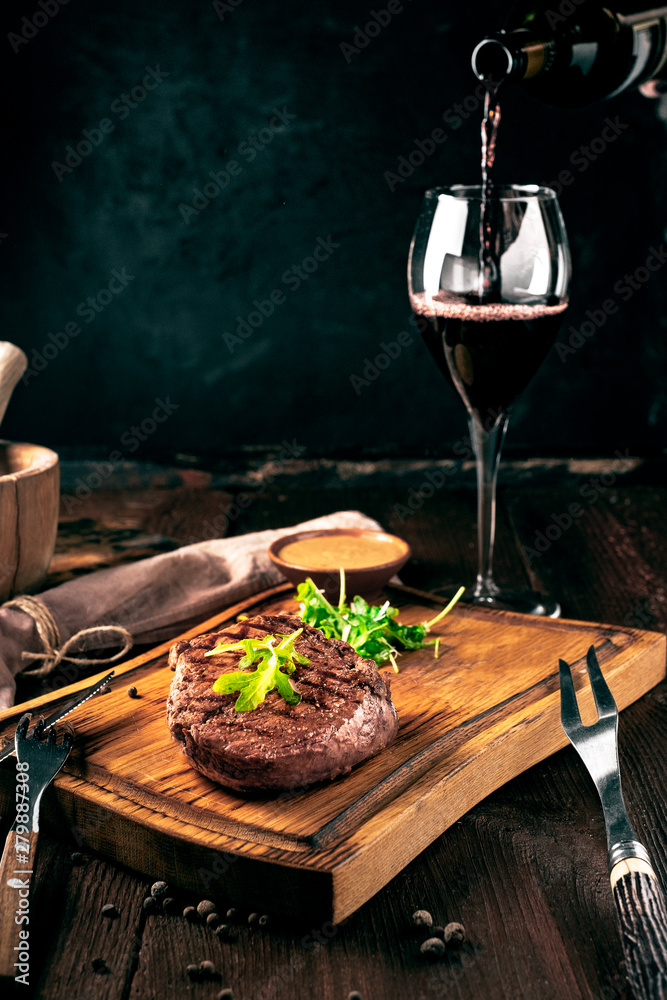 Wall mural grilled ribeye beef steak with wine, knife and fork on a wooden board. whole roast piece of meat, ru