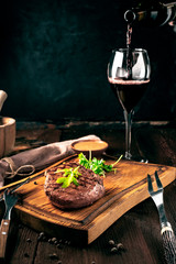 Grilled ribeye beef steak with wine, knife and fork on a wooden Board. Whole roast piece of meat,...