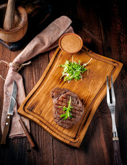 Grilled ribeye beef steak with knife and fork on a wooden Board. Top view and rustic style