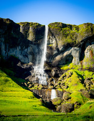 Waterfall in green mountain landscape in Iceland
