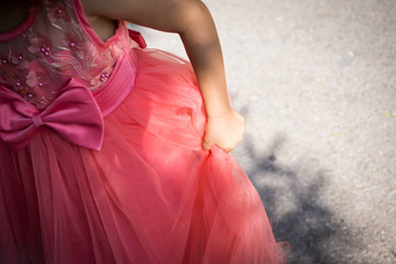Close-up of part of a little girl with a coral-dress princess dress. Shallow depth of focus.
