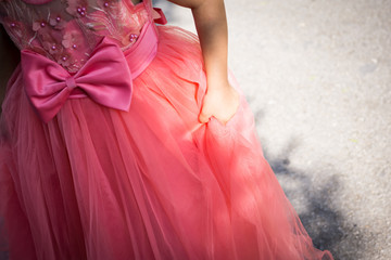Close-up of part of a little girl with a coral-dress princess dress. Shallow depth of focus.