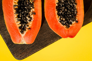 Fresh papaya exotic tropical fruit on yellow background. Sun day light illumination. Minimalistic summer flat lay wallpaper. Creative food concept. Copy space template. Bold colors