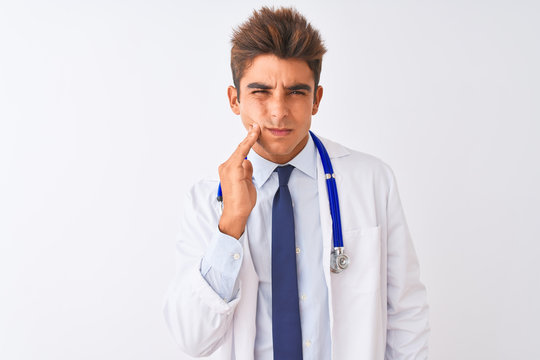 Young handsome doctor man wearing stethoscope over isolated white background touching mouth with hand with painful expression because of toothache or dental illness on teeth. Dentist concept.