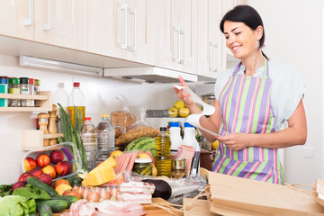 Woman is standing with check and satisfied of the prices of food at home.