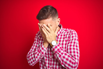 Young handsome man over red isolated background with sad expression covering face with hands while crying. Depression concept.