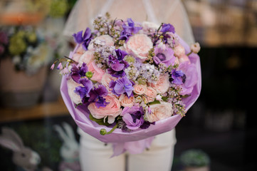 Girl holding a bouquet of violet and tender rose colour flowers