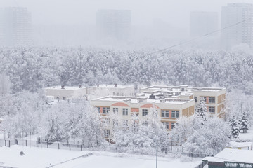 Snowy weather at Moscow district. Snow-covered trees and buildings in winter