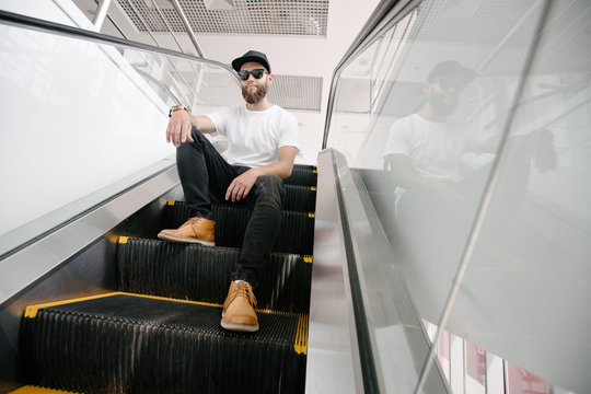 Portrait of a Hipster man with the beard close up. He is standind on an escaator